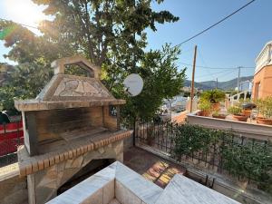 a stone outdoor fireplace on a balcony with a fence at Crystal seaview home in Iraklitsa