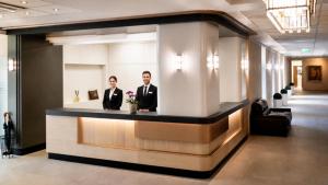 a man and a woman standing at a reception counter in a lobby at Hotel Garzon Plaza in Győr +64 photos