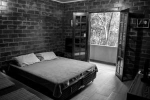 Un dormitorio con una cama y una pared de ladrillo. en Refúgio Melissa, en Campos do Jordão
