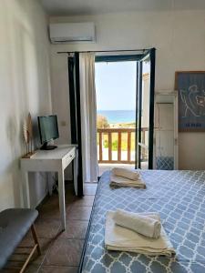 a bedroom with a bed and a desk and a window at Cyclades Serenity Beach House in Kipri