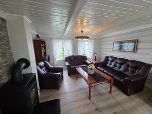 a living room with leather couches and a coffee table at Fiskehuset Havnes in Averoy