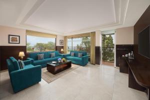 a large living room with blue couches and a television at Fortune Park Moksha, Mcleodganj - Member ITC Hotels' Group in McLeod Ganj
