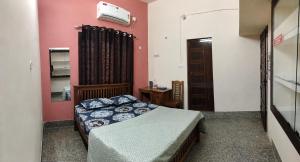 a bedroom with a bed in a room with pink walls at Devaki Tourist Home in Ambalapulai
