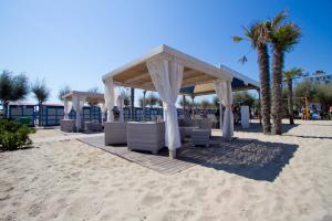 a pavilion on the beach with chairs and palm trees at Alba Appartamenti in Sottomarina