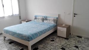 a bedroom with a bed with blue sheets and pillows at Alba Appartamenti in Sottomarina
