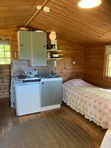 a kitchen in a log cabin with a bed at Aggarps Stugor in Kulltorp