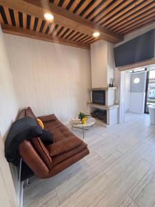 a living room with a brown couch and a table at Mar no Camiño. Terraza, bañera con vista al mar. in Brens