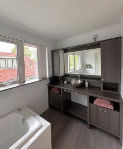 a bathroom with a sink and a tub and a mirror at B&B Wetterwille in Opeinde +14 photos