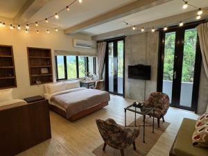 a bedroom with a bed and a tv and some chairs at 泰森會館 in Lugu Lake