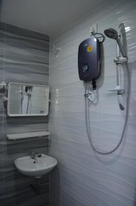 une salle de bain avec douche et lavabo dans l'établissement Tanjung Homestay, à Ipoh