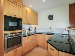 a kitchen with wooden cabinets and a clock on the wall at 24 The Salcombe in Salcombe