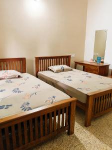 two beds sitting next to each other in a room at Devaki Tourist Home in Ambalapulai