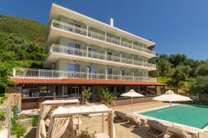 a large building with a swimming pool and umbrellas at Corfelia Seaview Suites in Ipsos