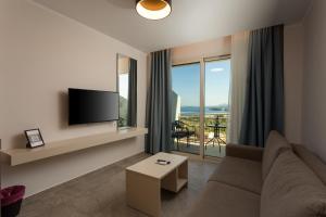 a living room with a couch and a flat screen tv at Corfelia Seaview Suites in Ipsos