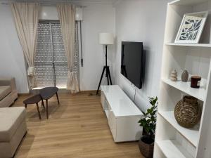 a white living room with a tv and a couch at Casa Borges in Quelfes