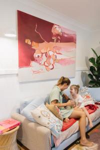 a woman and a child sitting on a bed at Lady Rose Cottage Jamberoo in Jamberoo