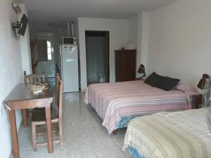 1 dormitorio con 2 camas, mesa y nevera en Canoas Apart en Colón
