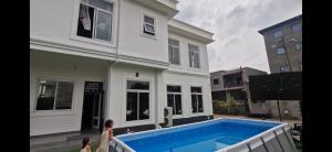a house with a blue swimming pool in front of it at The white house in Douala