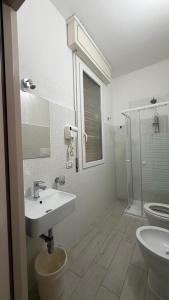 a white bathroom with a sink and a toilet at Hotel Primula in Lido di Savio +47 photos