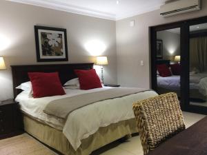 a bedroom with a bed with red pillows and a mirror at Polokwane Place in Polokwane