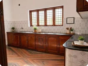 a kitchen with wooden cabinets and a counter top at Kandass Homestay in Trichūr