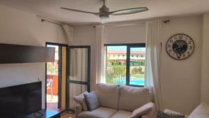 a living room with a couch and a clock on the wall at GLC Islantilla in Huelva