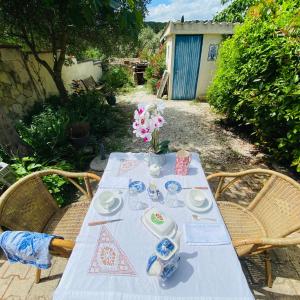 a table with plates and cups and a vase on it at La Maison aux coquillages in Portel-des-Corbières