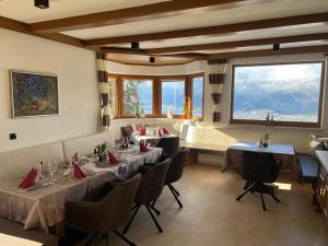 a dining room with tables and chairs and windows at Pension Erlerhof Chez Karin in Tulfes