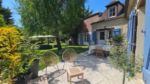 a patio with chairs and a table in a yard at L'Orée d'Ermenonville in Borest