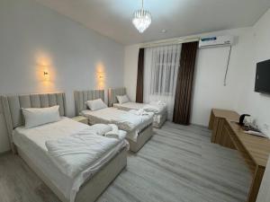 a hotel room with two beds and a television at ALAmir Khiva in Khiva