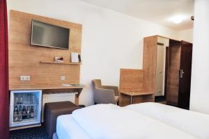 a hotel room with two beds and a tv on a wall at Hotel Poinger Hof in Poing