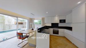a kitchen with white cabinets and a table and a dining room at Host Villas LA TIRMANAISE Capbreton in Capbreton