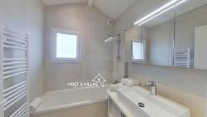 a bathroom with a tub and a sink and a mirror at Host Villas LA TIRMANAISE Capbreton in Capbreton