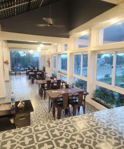 a dining room with tables and chairs and windows at Hotel Joy Guru Inn in Durgāpur