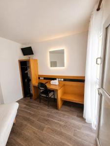 a room with a desk and a bed and a mirror at Mâcon Nord Hôtel, Ex Charme En Maconnais in Mâcon