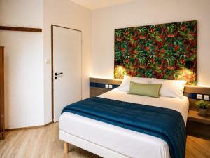 a bedroom with a bed with a painting on the wall at Mâcon Nord Hôtel, Ex Charme En Maconnais in Mâcon
