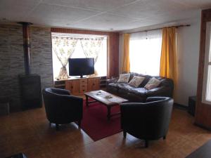 sala de estar con sofá y TV en Cabañas Rusticas en Coyhaique, en Coyhaique