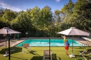 a person is standing next to a swimming pool at Gîte Des Myrtilles in Le Soulié