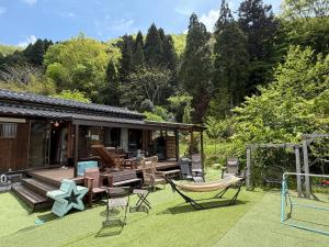 a backyard with a patio with chairs and a house at 1棟貸し サウナ&持込バーベキュー 露天風呂 囲炉裏 古民家 さえずり in Tamba-sasayama