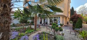 a building with tables and chairs in a garden at Family нouse -Нotel Asai in Ravda