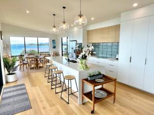 a kitchen with white cabinets and a table with chairs at Coastal Luxe Villa in Kakanui