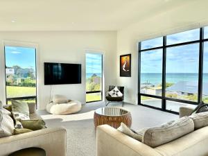 a living room with two couches and a flat screen tv at Coastal Luxe Villa in Kakanui
