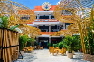 a restaurant with tables and chairs in front of a building at Happy Bear Hostel Phu Quoc in Phú Quốc