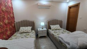 a room with two beds and a table with a lamp at 2 BHK Starry Night Penthouse in Islamabad