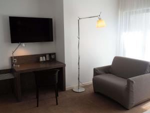 a living room with a chair and a desk with a television at Mercure Saint Malo Balmoral in Saint Malo