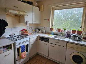 a kitchen with a stove and a sink and a window at Nad's Guest house in Motherwell