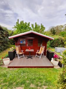 a small red cabin with two chairs on a deck at Apfelhof Rüdersdorf in Rüdersdorf