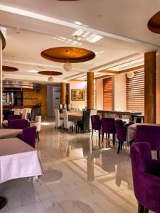 a dining room with tables and purple chairs at Hotel Dabi Imperial in Donji Štoj