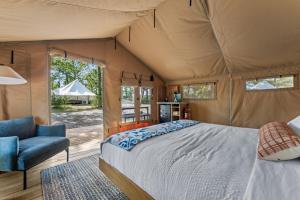 a bedroom in a tent with a bed and a chair at Glamping Tent, Hike, Smore Vibes in Branson