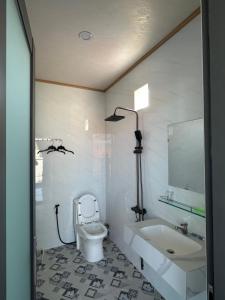 a white bathroom with a toilet and a sink at Motel Mỹ Linh 976 in Long Hai